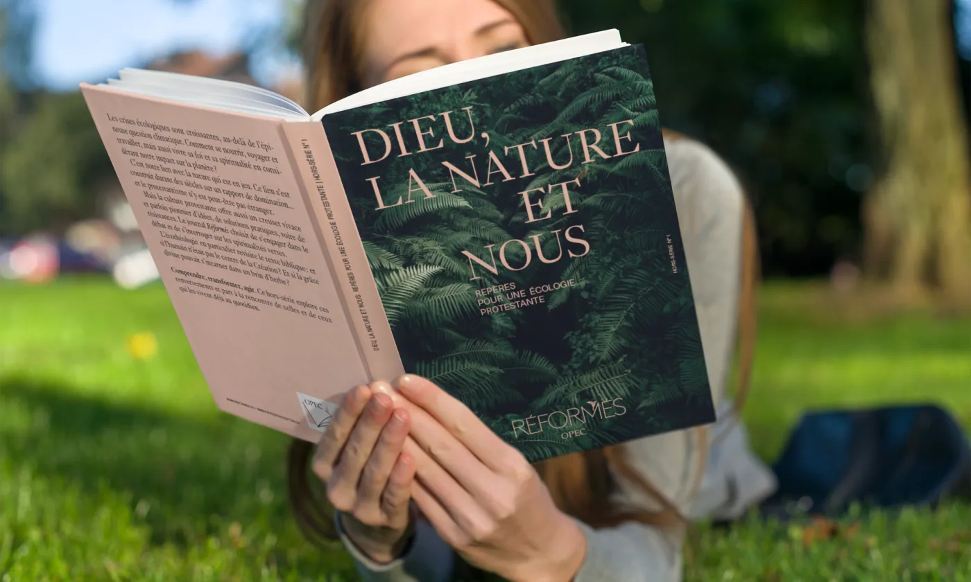 Le mook « Dieu, la nature et nous, Repères pour une écologie protestante» lu dans un pré. Photomontage (Eh oui, notre mook est en cours de fabrication)